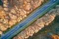 Aerial view of intercity road with fast driving cars between autumn forest trees at sunset. Top view from drone of Royalty Free Stock Photo