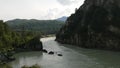 Aerial view of the Katun river and a fast boat floating on the river. The river is bluish-gray. Travel to Altai in summer.
