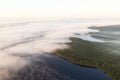 Aerial view lake with fog above water surface and sunrise over forest. Top view amazing seashore with fog over the water and green Royalty Free Stock Photo