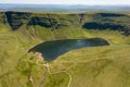 Aerial view of a lake formed at the base of green mountains Llyn y Fan Fach, Brecon Beacons, Wales