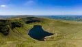 Aerial view of a lake formed at the base of green mountains Llyn y Fan Fach, Brecon Beacons, Wales