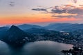 Aerial view of the lake Lugano surrounded by mountains and evening city Lugano on during dramatic sunset, Switzerland, Alps. Royalty Free Stock Photo