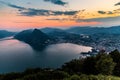 Aerial view of the lake Lugano surrounded by mountains and evening city Lugano on during dramatic sunset, Switzerland, Alps. Royalty Free Stock Photo