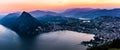 Aerial view of the lake Lugano surrounded by mountains and evening city Lugano on during dramatic sunset, Switzerland, Alps. Royalty Free Stock Photo