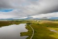 Aerial view on a lake and a small road to a mountains. Vast empty green fields. Connemara, county Galway, Ireland. Travel and