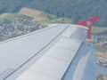 Aerial view of land and wing through porthole of Edelweiss air aircraft