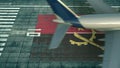 Aerial view of a landing airliner and flag of Angola on the airfield of an airport. Air travel related conceptual 3D
