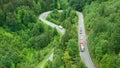 Aerial view of landscape curved road with moving firewood truck in mountains with high green trees