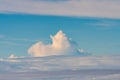 An aerial view of a large cloud looming over the smaller clouds