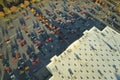 Aerial view of large parking lot in front of rgocery store with many parked colorful cars. Carpark at supercenter