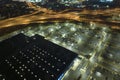 Aerial view of large parking lot at nighttime with many parked cars. Dark carpark at supercenter shopping mall with