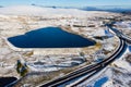 Aerial view of a large reservoir next to a major dual carriageway on a snowy day