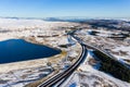 Aerial view of a large reservoir next to a major dual carriageway on a snowy day