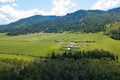 Aerial view of livestock plots and agricultural green fields in nature in the Altai Mountains with small houses. With blue sky and Royalty Free Stock Photo