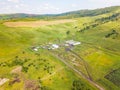 Aerial view of livestock plots and agricultural green fields in nature in the Altai Mountains with small houses. With blue sky and Royalty Free Stock Photo