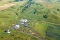 Aerial view of livestock plots and agricultural green fields in nature in the Altai Mountains with small houses of farm, tractors Royalty Free Stock Photo