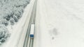 Aerial view of a logging truck driving on an empty road leading through snowy spruce forest. Scene. Concept of Royalty Free Stock Photo