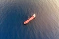 Aerial view of a lonely container ship sailing at blue sea water background. Water transportation and logistics concept. Red boat