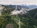 aerial view of a long lonely road at the bottom of the green valley between grass vegetation and forests next to the Royalty Free Stock Photo