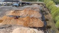 Aerial view of a lumberyard with piles of wood chips and a red loader Royalty Free Stock Photo