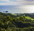 Aerial view of lush green grass hills with fields and pastures and famous volcanic islet near the coast, sea horizon Royalty Free Stock Photo