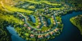 Aerial view of a lush, green planned residential community with winding roads, housing estates, sports fields, and water