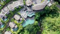 Aerial view of luxury hotel with straw roof villas and pools in tropical jungle and palm trees. Luxurious villa