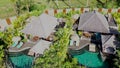 aerial view of luxury hotel with straw roof villas and pools in tropical jungle and palm trees. Young man on sofa on