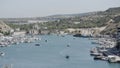 Aerial view of luxury port on a summer day with many yachts. Action. Summer small town with growing trees and mountains.