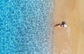 Aerial view of a lying woman in hat on sandy beach and blue sea Royalty Free Stock Photo