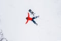 Aerial view of a man lying in the snow next to his snowboard