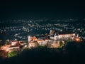 Aerial view of medieval castle on mountain at night in small european city in autumn season Royalty Free Stock Photo