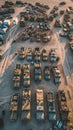 Aerial view of a military convoy arrayed on a remote dirt road at dusk, showcasing a systematic arrangement of tents and