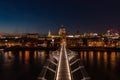 Aerial view of the Millennium Bridge walkway in London city with lights and people walking at night facing towards the Royalty Free Stock Photo