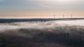 Aerial view of the misty morning woodland landscape with the group of modern tall wind turbines Royalty Free Stock Photo