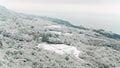 Aerial view of modern cottages on the slopes and mountain forest covered by snow near the coastline and sea in winter Royalty Free Stock Photo