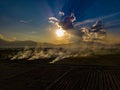 Aerial view. The morning sunrises with dry grass is burning on the field.