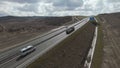 Aerial view of a motorway with driving cars and large cargo truck. Shot. Road built along endless fields on cloudy sky