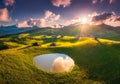 Aerial view of mountain village on green hills and pond at sunset