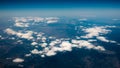 Aerial view of mountains under the clouds and blue sky. View from a plane window. Beautiful landscape Royalty Free Stock Photo