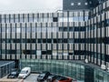 : Aerial view of multiple cars vans parked in front of modern large office