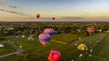 Aerial View of Multiple Hot Air Balloons Launching and Floating Away at Sunrise on a Sunny Morning