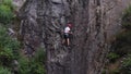 Aerial view muscular with red helmet rockclimber climb on tough sport route in mountain,searching,reaching and gripping