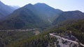 Aerial view of a narrow winding mountain road surrounded by lush green nature. Clip. Flying over the picturesque Royalty Free Stock Photo