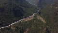 Aerial view of a narrow winding mountain road surrounded by lush green nature. Clip. Flying over the picturesque Royalty Free Stock Photo