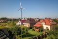 Aerial view of a new autonomous house with solar panels, water heating radiators on the roof and wind powered turbine on green