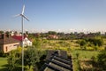 Aerial view of a new autonomous house with solar panels, water heating radiators on the roof and wind powered turbine on green