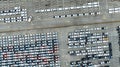 Aerial view of new cars stock at factory parking lot. Above view cars parked in a row. Automotive industry. Logistics business. Royalty Free Stock Photo
