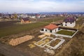 Aerial view of new house roof with attic windows and building site, foundation of future house, stacks of bricks and building