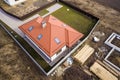 Aerial view of new house roof with attic windows and building site, foundation of future house, stacks of bricks and building